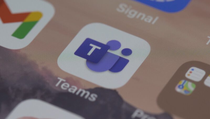 Close-up of the Microsoft Teams app icon on a smartphone screen, featuring a blue and purple logo with the word "Teams" displayed below. The context suggests a focus on collaboration and communication, relevant to Microsoft Teams SecOps collaboration.