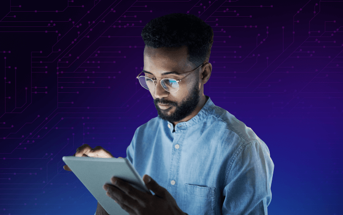 A man wearing glasses interacts with a tablet while standing against a digital circuit background. He is focused on the screen, dressed in a light blue shirt.