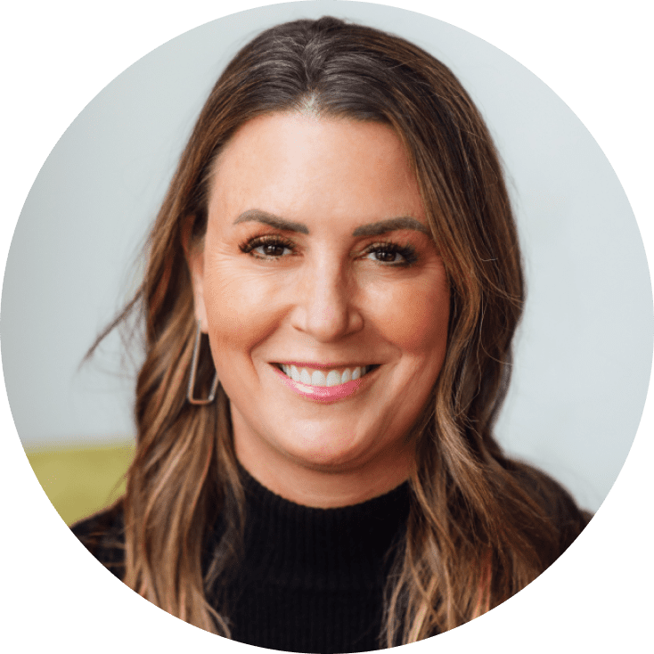 A close-up portrait of a woman with long brown hair, smiling warmly, wearing a black turtleneck sweater. The background is soft and light in color, creating a friendly atmosphere.
