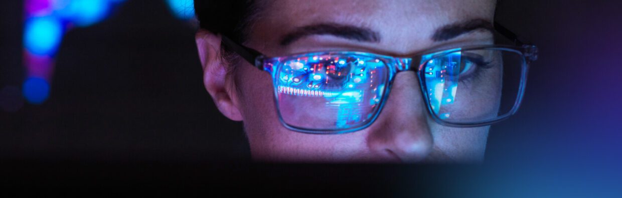 Close-up of a person's face wearing glasses, reflecting colorful data visualizations on the lenses, indicating engagement in data analysis or technology, relevant to utilizing machine learning operations and MLOps defined.