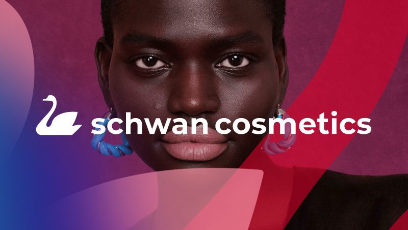 A close-up portrait of a model with dark skin and bold makeup, wearing blue earrings. The background features a gradient of pink and blue, with the text 'schwan cosmetics' prominently displayed.