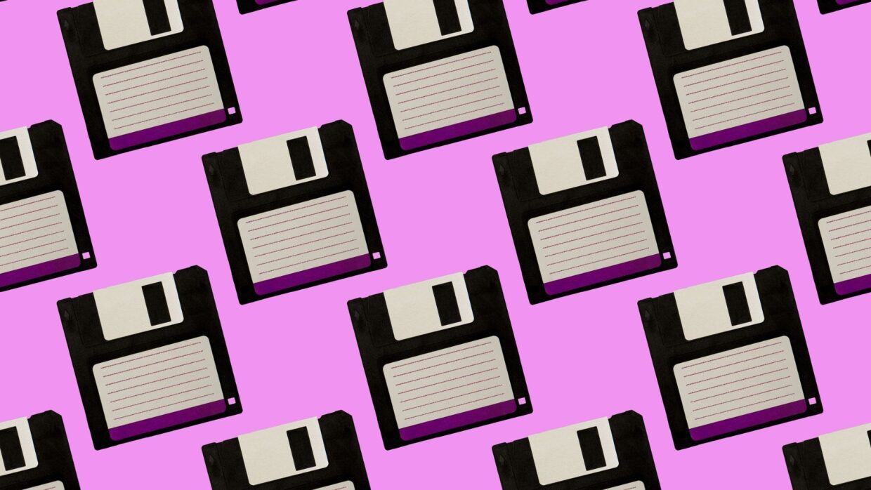 A pattern of black and white floppy disks on a pink background, illustrating retro technology and data storage, relevant to the History of Ransomware.