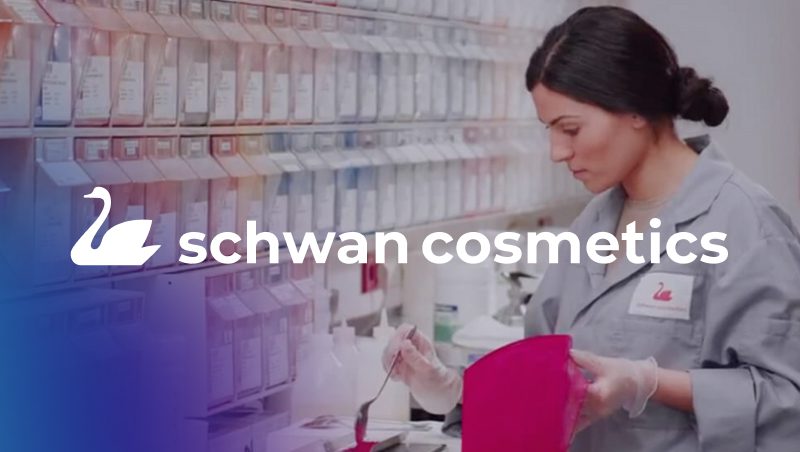 A woman in a lab coat mixing cosmetics in a laboratory, surrounded by organized containers. The Schwan Cosmetics logo is prominently displayed in the foreground.