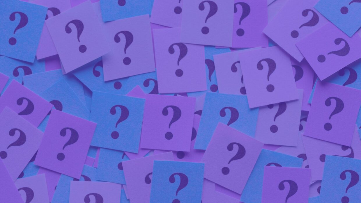 A collage of small square notes in shades of purple, each featuring a black question mark. The vibrant colors and patterns create a visually engaging backdrop, symbolizing inquiry and curiosity, relevant to discussions about Agentic AI.